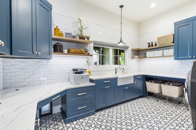 kitchen featuring hanging light fixtures, blue cabinetry, and light stone counters