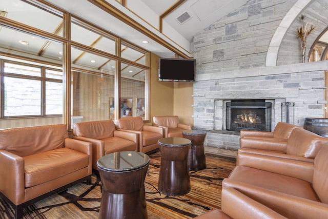 living room with hardwood / wood-style flooring, high vaulted ceiling, a stone fireplace, and beamed ceiling