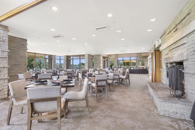 carpeted dining area featuring floor to ceiling windows and a stone fireplace