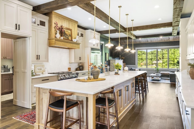 kitchen featuring a large island with sink, beam ceiling, white cabinetry, and a kitchen breakfast bar