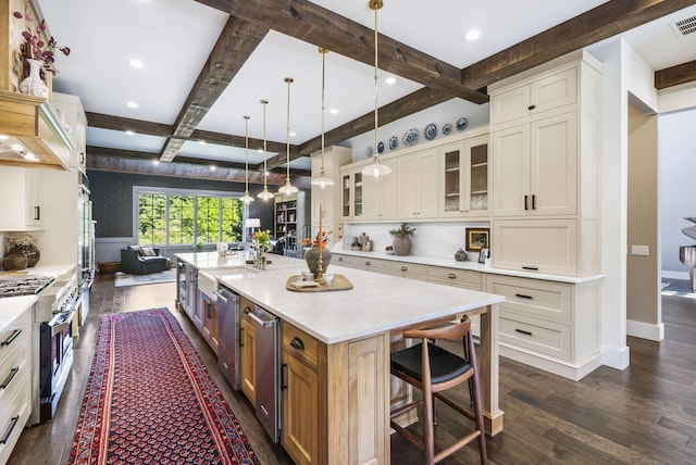 kitchen with coffered ceiling, dark hardwood / wood-style floors, stainless steel appliances, hanging light fixtures, and a spacious island