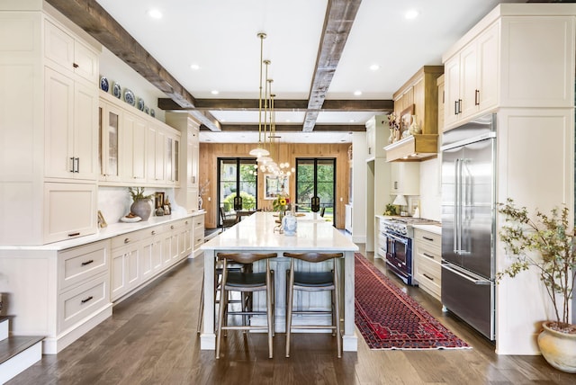 kitchen featuring a center island with sink, high end appliances, white cabinetry, and decorative light fixtures