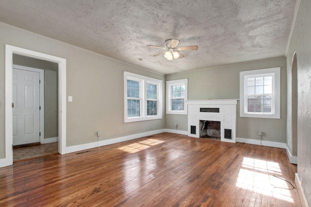 unfurnished living room with ceiling fan, a fireplace, dark hardwood / wood-style floors, ornamental molding, and a textured ceiling