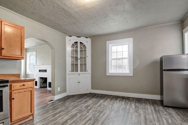 kitchen with crown molding, stainless steel refrigerator, dark hardwood / wood-style flooring, and a textured ceiling