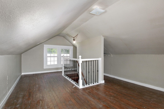 bonus room featuring a textured ceiling, lofted ceiling, and dark hardwood / wood-style flooring