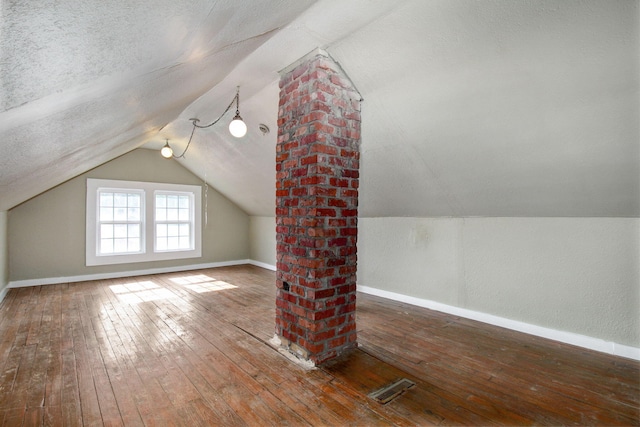 bonus room featuring lofted ceiling, dark hardwood / wood-style floors, and a textured ceiling