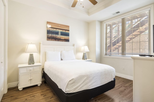 bedroom featuring ceiling fan, a tray ceiling, crown molding, and dark hardwood / wood-style flooring