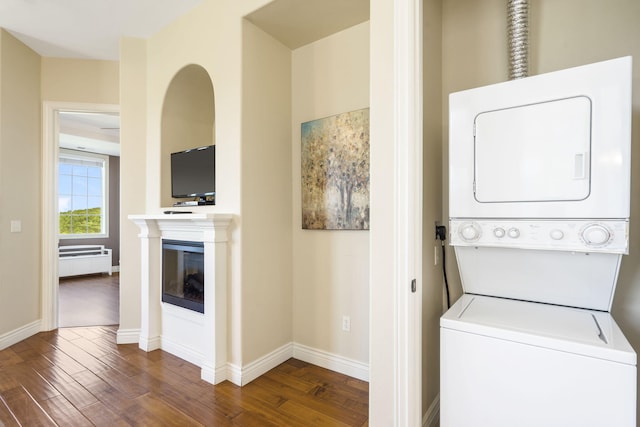 washroom featuring stacked washing maching and dryer and dark hardwood / wood-style flooring