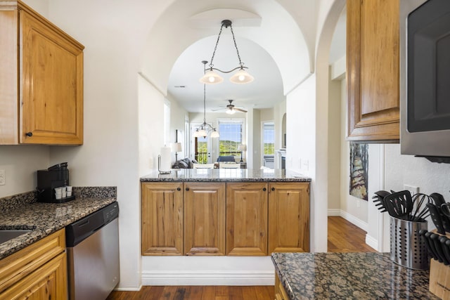 kitchen featuring ceiling fan, stainless steel appliances, dark stone countertops, dark hardwood / wood-style flooring, and decorative light fixtures