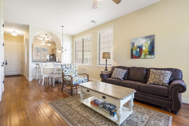 living room with ceiling fan with notable chandelier, dark hardwood / wood-style flooring, and a wealth of natural light