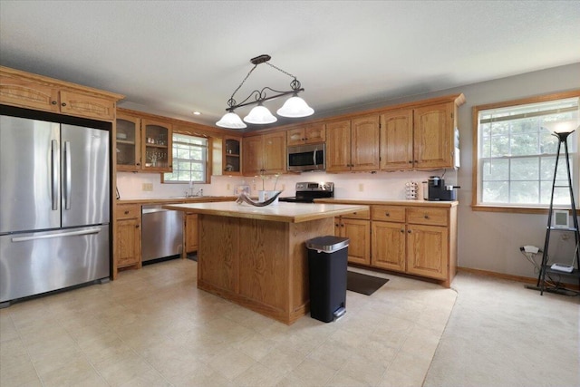 kitchen featuring stainless steel appliances, pendant lighting, sink, and a center island