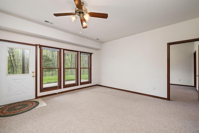 spare room with baseboards, visible vents, light colored carpet, and ceiling fan