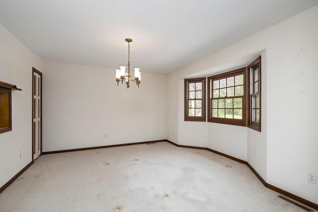 spare room with light carpet, baseboards, visible vents, and a chandelier