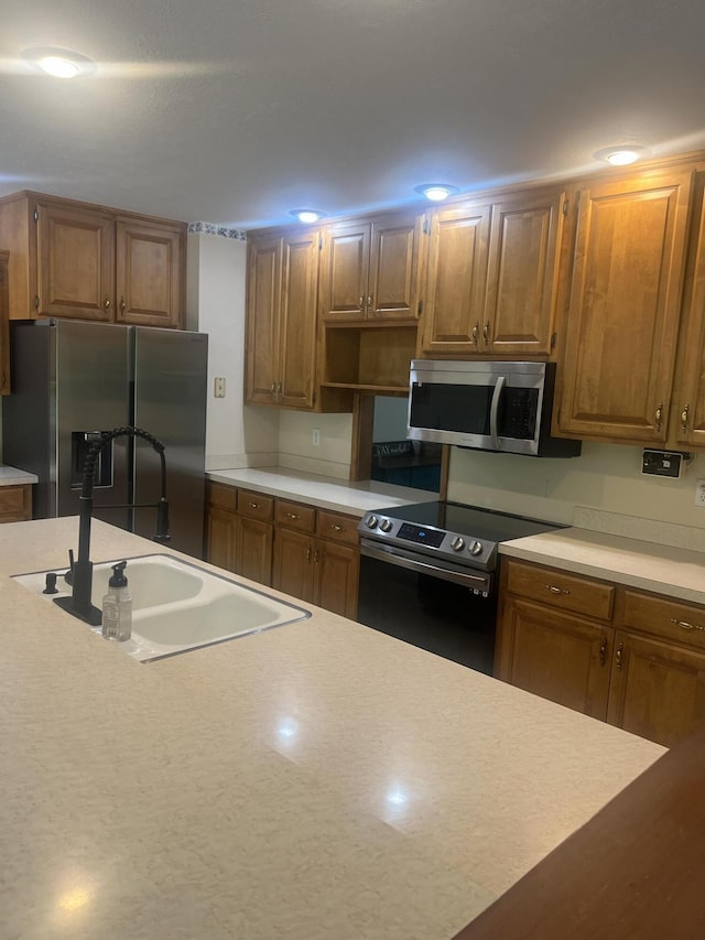 kitchen with light countertops, a sink, brown cabinets, and appliances with stainless steel finishes