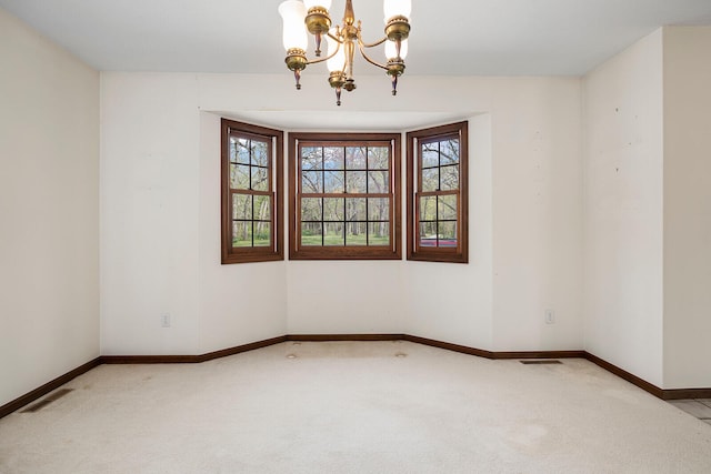 empty room with light colored carpet and a chandelier