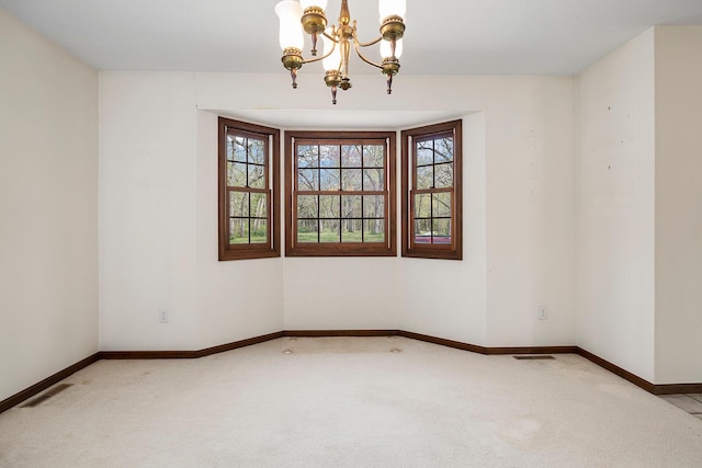 spare room with plenty of natural light, baseboards, an inviting chandelier, and light colored carpet