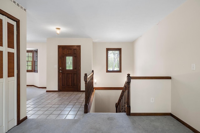 entryway featuring light carpet, light tile patterned flooring, and baseboards