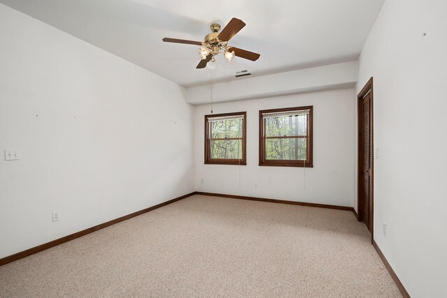 empty room with baseboards, a ceiling fan, visible vents, and light colored carpet