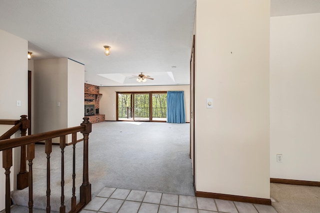 spare room featuring light carpet, a brick fireplace, a skylight, and a raised ceiling