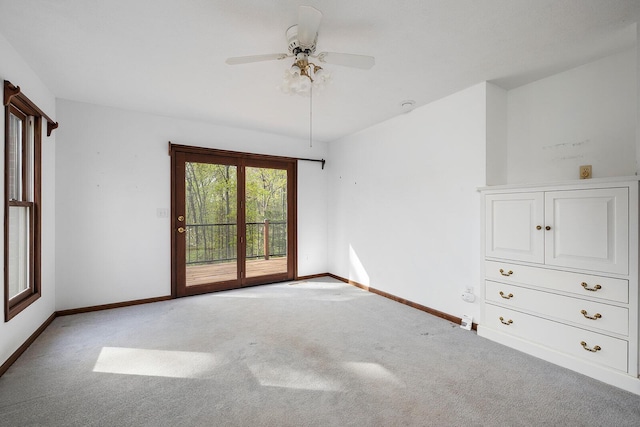carpeted spare room featuring a ceiling fan and baseboards