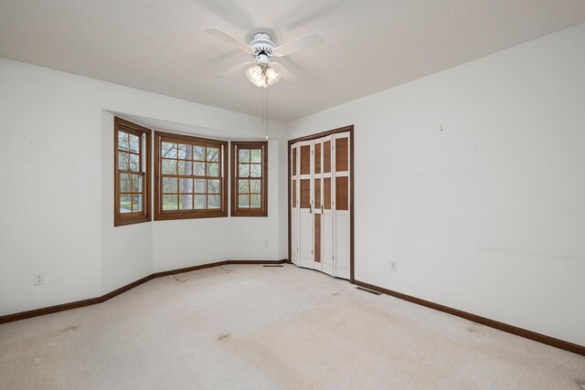 carpeted empty room featuring visible vents, baseboards, and ceiling fan