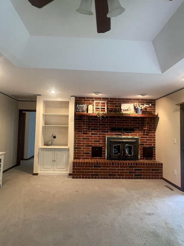 unfurnished living room featuring a ceiling fan, built in shelves, carpet floors, lofted ceiling, and a brick fireplace