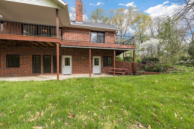 back of property with brick siding, a patio area, a lawn, and a chimney
