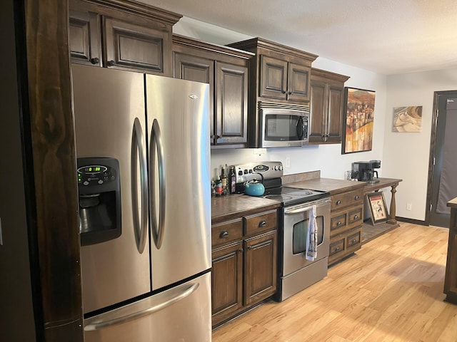 2800 Briaroaks Ln, Joplin, MO 64804 - kitchen featuring dark countertops, light wood-style flooring, dark brown cabinetry, and appliances with stainless steel finishes