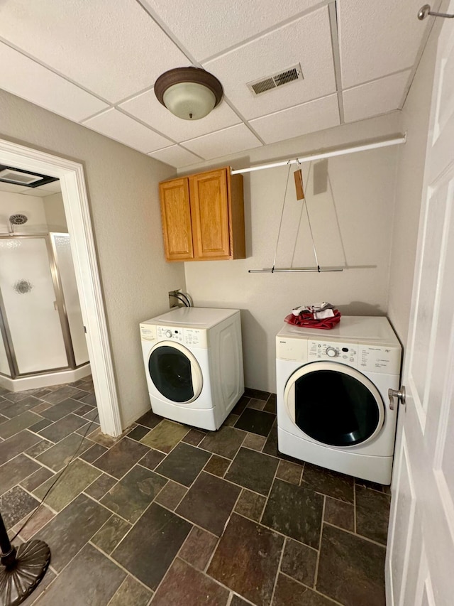 laundry room with separate washer and dryer and cabinets