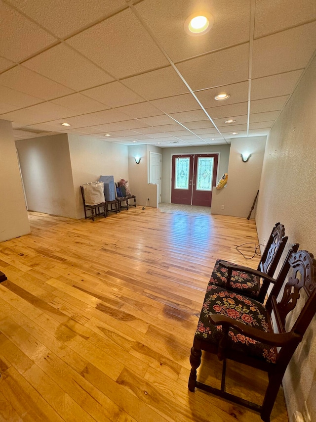 living area with a paneled ceiling, wood-type flooring, and french doors