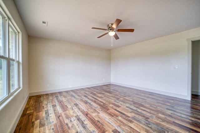 unfurnished room with a textured ceiling, a healthy amount of sunlight, ceiling fan, and dark hardwood / wood-style flooring