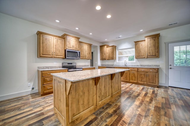 kitchen featuring appliances with stainless steel finishes, plenty of natural light, dark wood-type flooring, and a kitchen island