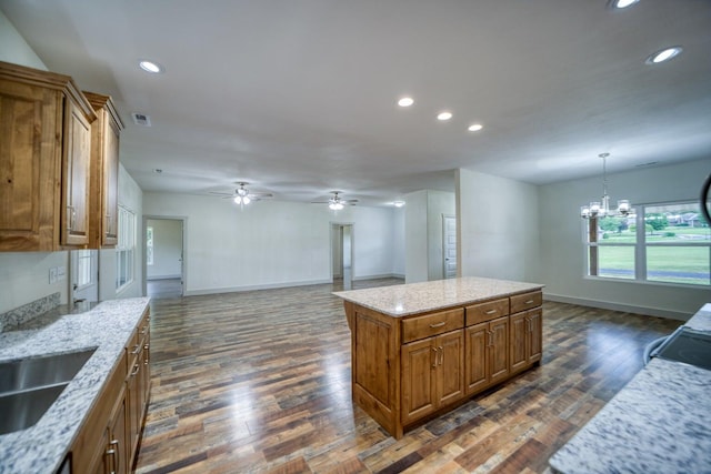 kitchen featuring light stone countertops, decorative light fixtures, dark hardwood / wood-style flooring, and a center island