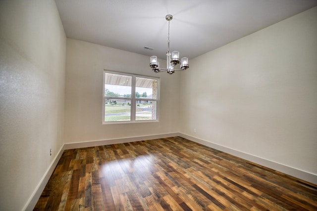 empty room with an inviting chandelier and dark hardwood / wood-style flooring