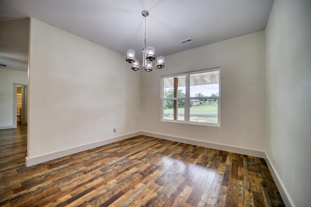 unfurnished room featuring a notable chandelier and dark hardwood / wood-style flooring