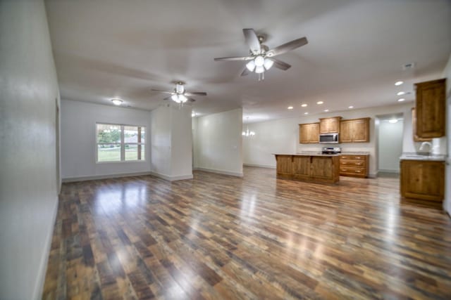 unfurnished living room featuring ceiling fan with notable chandelier and dark hardwood / wood-style flooring