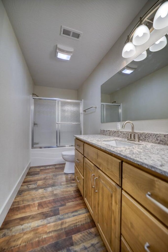 full bathroom with shower / bath combination with glass door, vanity, toilet, and hardwood / wood-style flooring