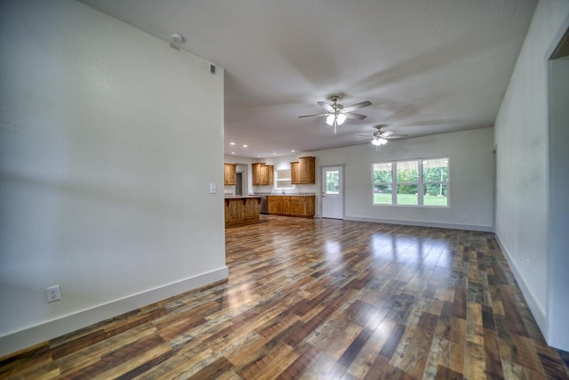 unfurnished living room with ceiling fan and dark wood-type flooring