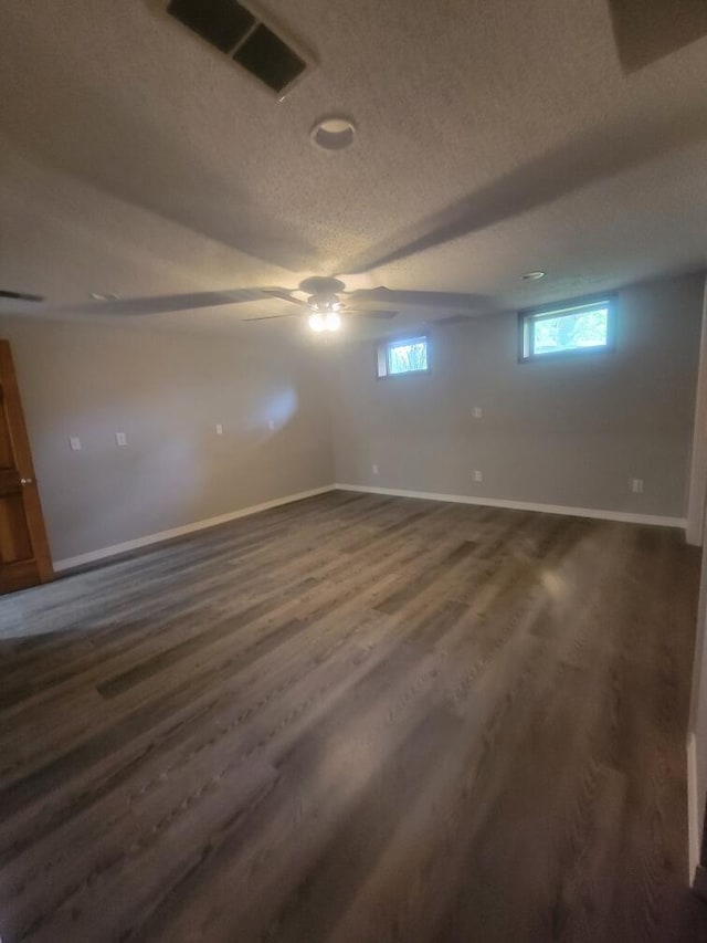 basement featuring ceiling fan, a textured ceiling, and dark wood-type flooring