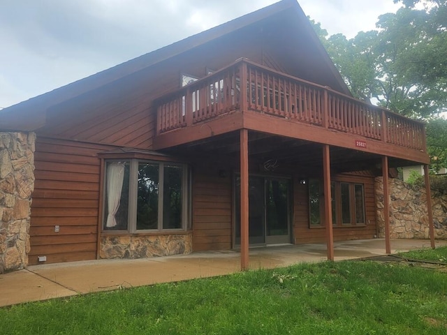 back of property with a patio area, stone siding, and a wooden deck