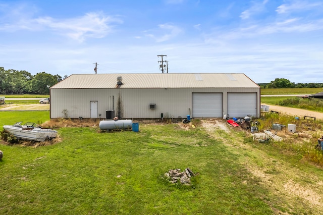 back of property with an outdoor structure, a garage, and a lawn