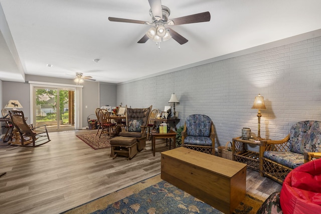 living room featuring brick wall, hardwood / wood-style flooring, and ceiling fan