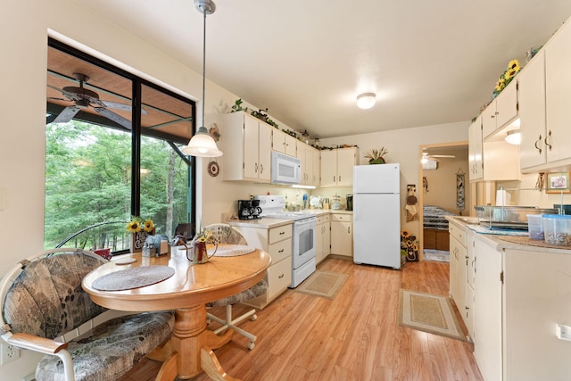 kitchen featuring white appliances, light hardwood / wood-style floors, white cabinets, and decorative light fixtures