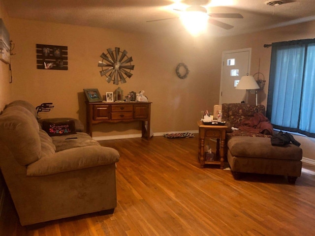 living room featuring ceiling fan, baseboards, and wood finished floors