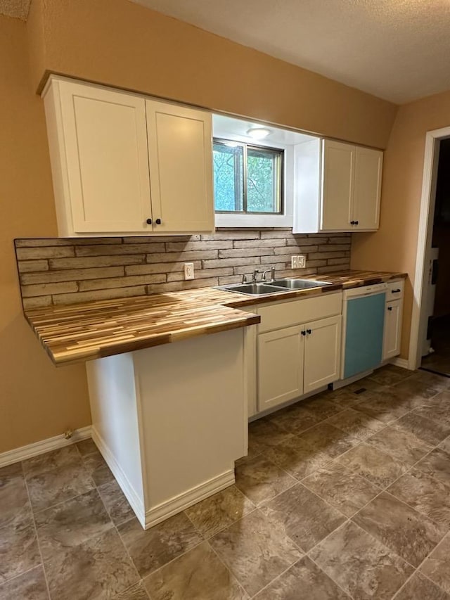 kitchen with white dishwasher, sink, butcher block countertops, white cabinetry, and decorative backsplash