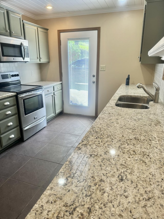 kitchen with crown molding, a sink, decorative backsplash, stainless steel appliances, and light stone countertops