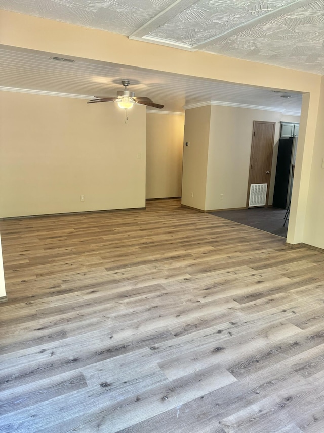 empty room with ceiling fan, wood finished floors, and visible vents