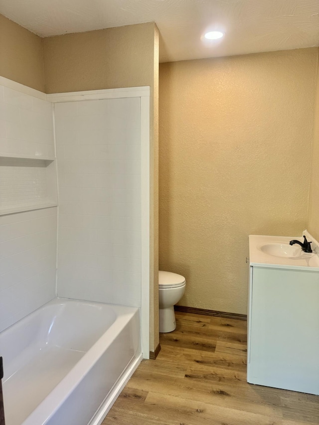 full bathroom with wood finished floors, toilet, vanity, and a textured wall
