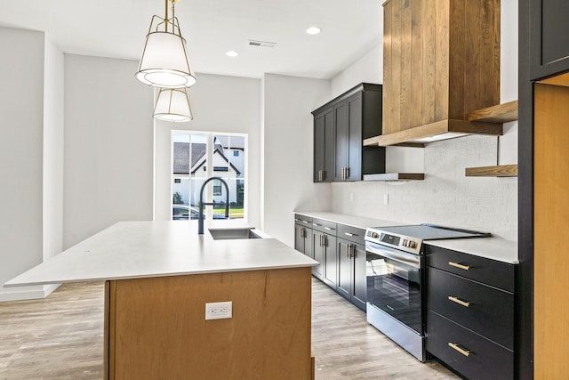 kitchen featuring sink, light hardwood / wood-style floors, pendant lighting, a center island with sink, and stainless steel electric range