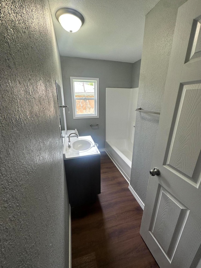 bathroom featuring vanity, a shower, hardwood / wood-style floors, and a textured ceiling